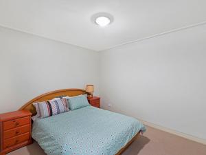 Un dormitorio con una cama con cabecero de madera y una cómoda. en Coast Apartment 12, en The Entrance