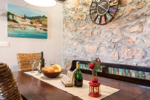 a dining room table with a clock on a stone wall at Apartman Lidija in Risika