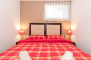 a bedroom with a red bed with two red pillows at Apartman Lidija in Risika