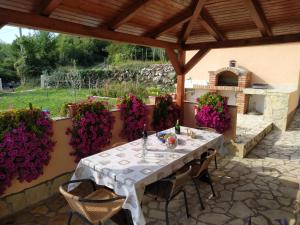un tavolo e sedie su un patio con fiori viola di Apartman Lidija a Risika