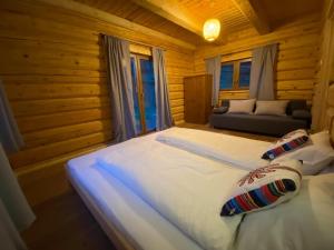a large white bed in a wooden room with a couch at Chata u Pietrka in Szczyrk