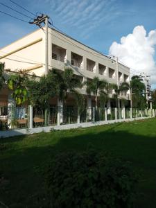 a large white building with a lawn in front of it at โรงแรมเวลลิงตัน in Ban Chak Phai