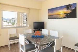 ein Esszimmer mit einem Tisch mit Stühlen und einem TV in der Unterkunft El Raco, A-7-13 in Cullera