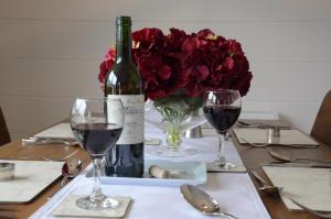 una mesa con una botella de vino y un jarrón de rosas rojas en Hollicarrs - Honeycomb Lodge, en York