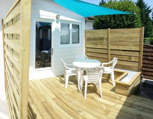 eine Holzterrasse mit einem Tisch, Stühlen und einem Sonnenschirm in der Unterkunft Maisonnette bois flottés in Salles