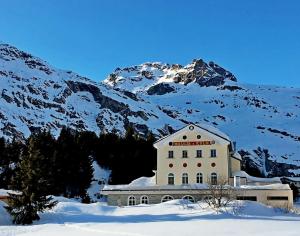 a building in the snow in front of a mountain at Maloja Kulm Hotel in Maloja