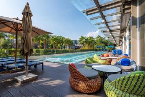 an outdoor patio with tables and chairs and a swimming pool at Maitria Hotel Rama 9 Bangkok - A Chatrium Collection in Bangkok