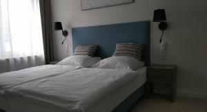 Bett mit blauem Kopfteil und 2 Kissen in der Unterkunft Aquamarina ONYX 13 in Misdroy