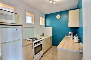 - une cuisine avec des murs bleus et des plaques de cuisson blanches dans l'établissement Appartement confortable en front de mer pour 5 personnes, à Valras-Plage