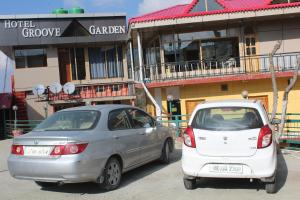 two cars parked next to each other in front of a building at THE GROOVE GARDEN DHANOLTi in Dhanaulti