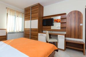 a bedroom with a bed and a desk and a television at Pansion Croatia in Starigrad