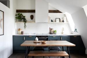 een keuken met blauwe kasten en een houten tafel bij Cosy Loft Apartment - minutes from Angel Tube St. in Londen