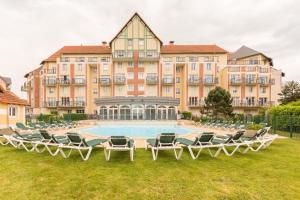 a large building with chairs and a swimming pool at Residence Pierre & Vacances Port Guillaume in Dives-sur-Mer