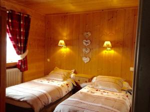 two beds in a room with wooden walls at Chalet la Tovasse in Notre-Dame-de-Bellecombe