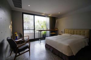 a bedroom with a bed and a chair and a window at 3 Door Hotel in Tainan