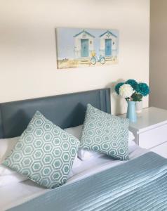 ein Bett mit zwei Kissen und ein Bild von einem Strand in der Unterkunft Pavilion Holiday Apartments in Weston-super-Mare