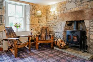 a living room with a wood stove and two chairs at The Lagg in Lagg