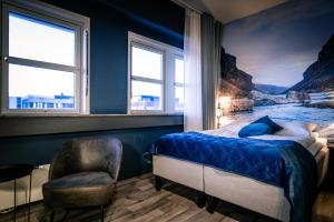a bedroom with a bed and a chair and windows at Canyon Hotell in Alta