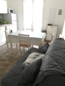 eine Küche mit einem Tisch, einem Tisch und einem Sofa in der Unterkunft Le sable chaud in Saint-Pierre-dʼOléron