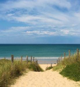 une plage de sable avec une clôture et l'océan dans l'établissement Le sable chaud, à Saint-Pierre-dʼOléron