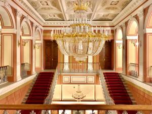Großes Zimmer mit einem großen Kronleuchter und einer Treppe in der Unterkunft Taleon Imperial Hotel in Sankt Petersburg