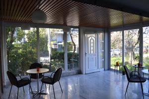 una stanza con tavoli, sedie e porte scorrevoli in vetro di Rivitel Marousi Apartments ad Atene