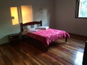 um quarto com uma cama com um cobertor rosa em Casa de Campo - Cambará do Sul em Cambará