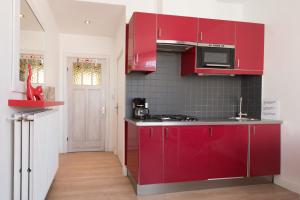 a kitchen with red cabinets and a stove at Appartement Le Lavandou in De Panne