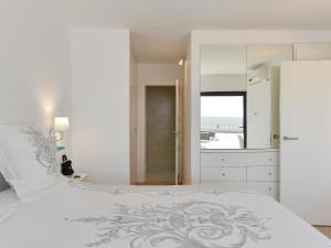 een witte slaapkamer met een groot bed en een spiegel bij Sea Haven 101 by VillaGranCanaria in San Agustin