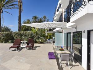 een patio met stoelen en een tafel met een witte parasol bij Sea Haven 101 by VillaGranCanaria in San Agustin