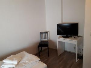 een kamer met een televisie en een bureau met een stoel bij Ferienwohnungen Haus Scheidter 42 in Saarbrücken