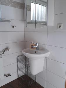 a white bathroom with a sink and a mirror at Ferienwohnungen Haus Scheidter 42 in Saarbrücken