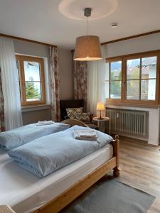 Schlafzimmer mit einem Bett, einem Stuhl und Fenstern in der Unterkunft Amelie Ferienwohnung in Garmisch-Partenkirchen