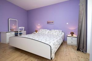 ツリクヴェニツァにあるAdriatic Apartmentsの紫の壁のベッドルーム1室(大きな白いベッド1台付)