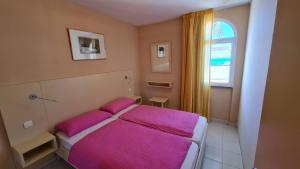 a bedroom with a bed with pink sheets and a window at Cura Sol in Playa del Cura