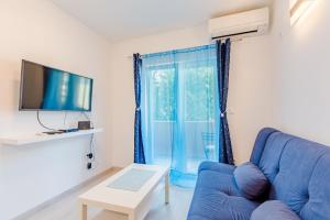 un salon avec un canapé bleu et une télévision dans l'établissement Apartment Karlo, à Kaštela