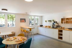 a kitchen with a table and chairs and a counter at Citadines Antigone Montpellier in Montpellier