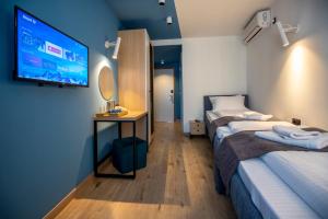 Una habitación con dos camas y un televisor en la pared. en Hotel 4 Llulla, en Pristina