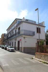 een wit gebouw met auto's geparkeerd aan de zijkant van een straat bij La stanza vicino al mare , una camera da letto e bagno con balcone vista mare in Balestrate
