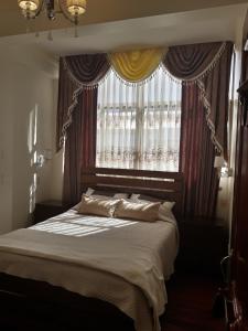1 dormitorio con 1 cama y una ventana con cortinas en Hostal Terrabella SRL, en La Paz