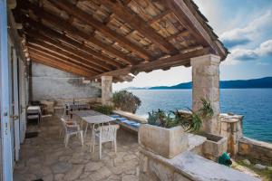 eine Terrasse mit einem Tisch, Stühlen und Wasser in der Unterkunft Holiday Home Ratac Sunshine Beach in Slano