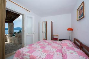 a bedroom with a bed with a pink comforter at Holiday Home Ratac Sunshine Beach in Slano