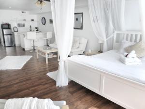 a white bedroom with a bed and a living room at Romantic Studio Cottage in Lambton Shores