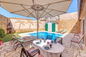 eine Terrasse mit einem Tisch, Stühlen und einem Pool in der Unterkunft Can Botellas in Petra