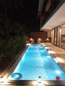 una piscina por la noche con sillas alrededor en The Cloverleaf Super Luxury Villa Goa With Private Pool, North Goa, en Candolim