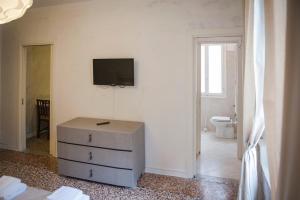 Pokój z komodą i telewizorem na ścianie w obiekcie Porta Orientalis Venice w Wenecji