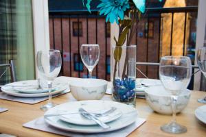 a table with plates and glasses and a vase with a blue flower at Grand Central Friar Gate Deluxe Apartments in Derby