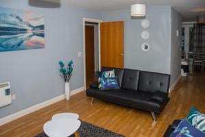 a living room with a black leather couch at Grand Central Friar Gate Deluxe Apartments in Derby