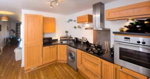 una cucina con mobili in legno e un apparecchio in acciaio inossidabile di Grand Central Friar Gate Deluxe Apartments a Derby