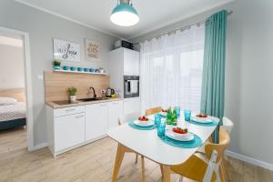 a kitchen and dining room with a white table and chairs at Plażowe Apartamenty Grzybowo in Grzybowo